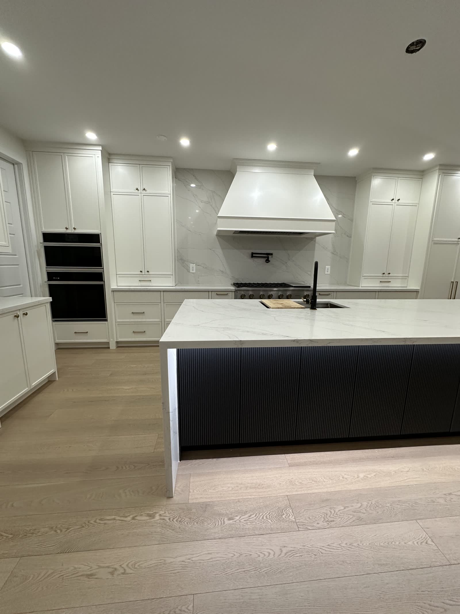White kitchen with a black fluted island and a panelled hood surround