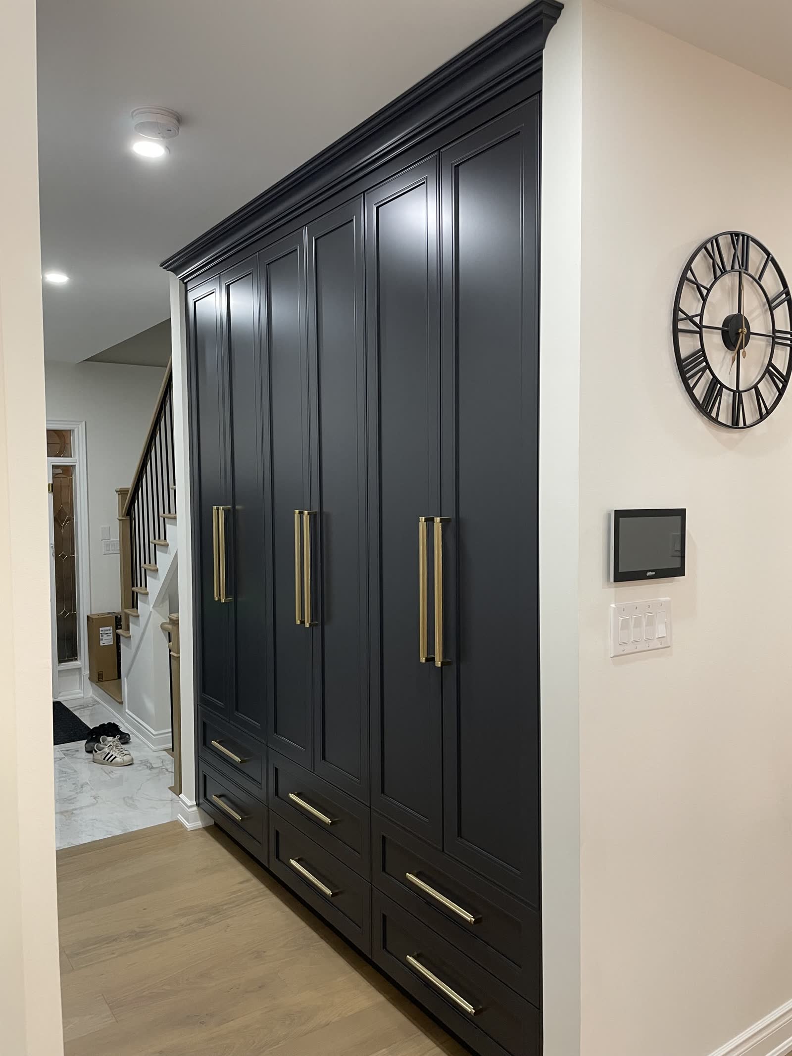 Fitted hall wardrobes in charcoal with a moulded cornice and brass handles